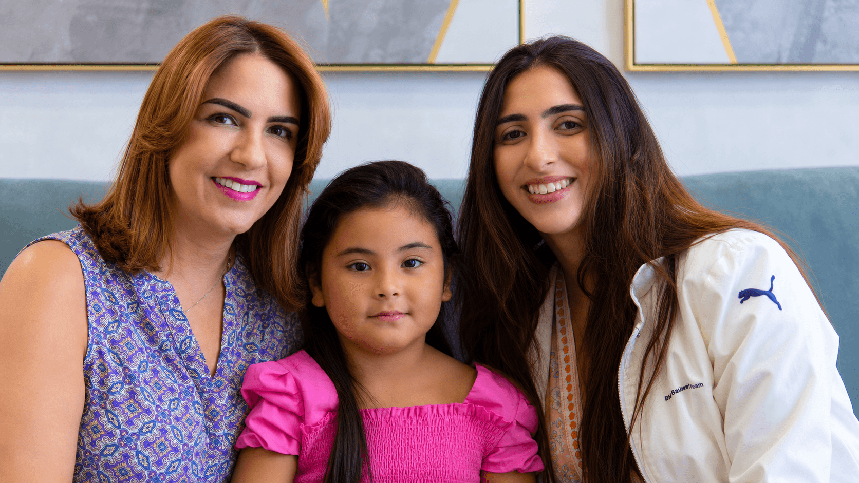 Dos mujeres y una niña posan juntas en la sala de espera de PAUDENT.